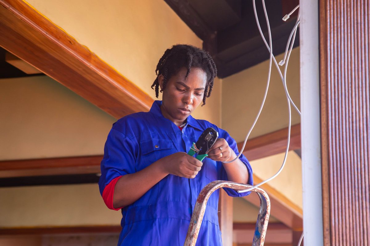 An electrician on a ladder working on wiring