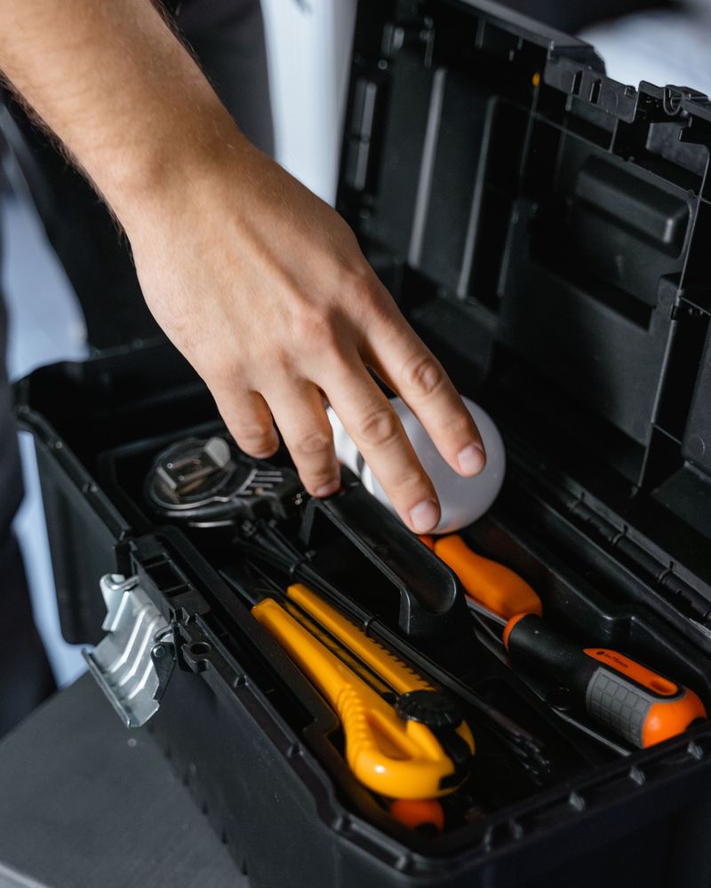 A hand reaching into an open toolbox